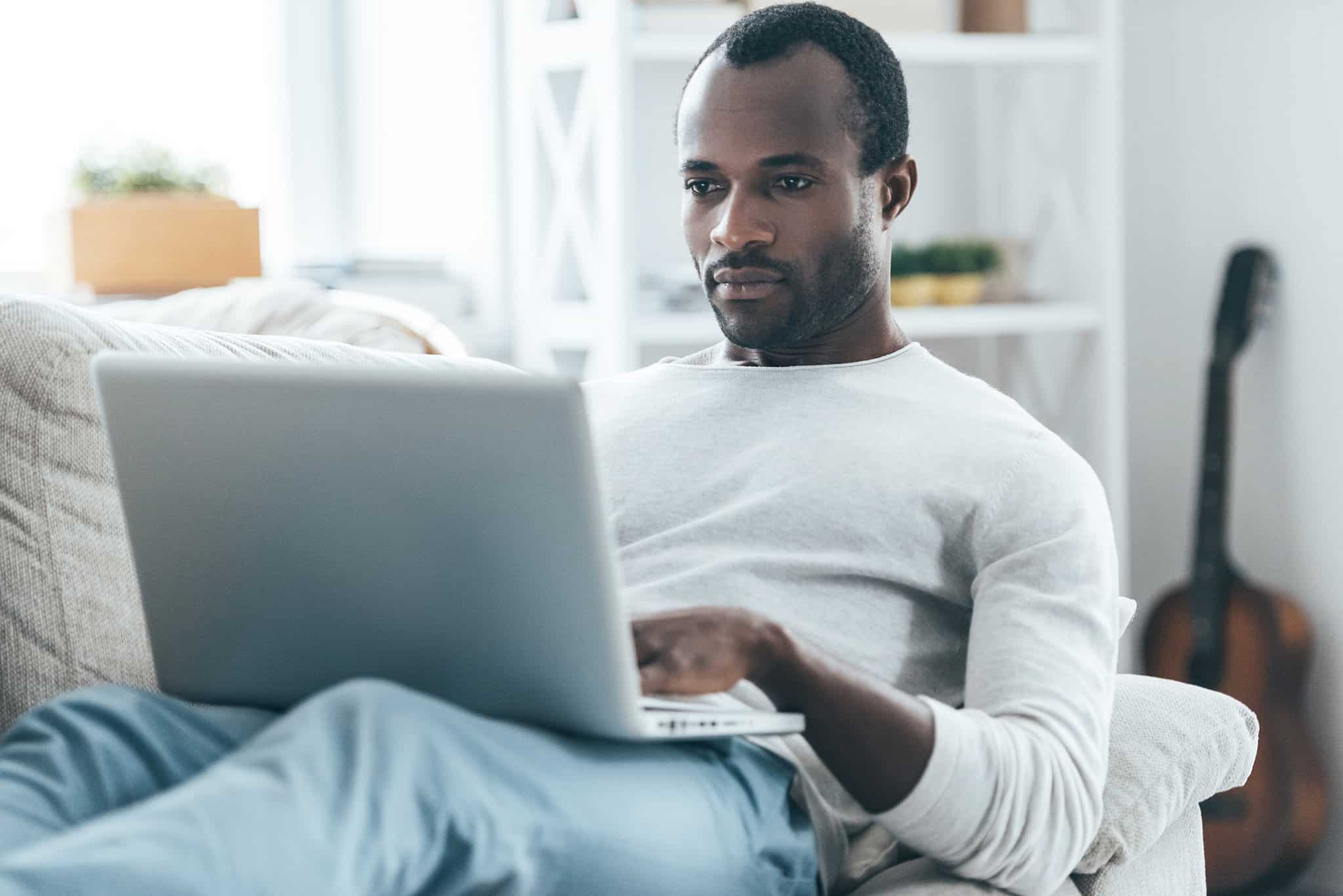 A man sitting on a couch using a laptop.