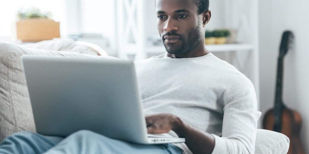 A man sitting on a couch using a laptop.