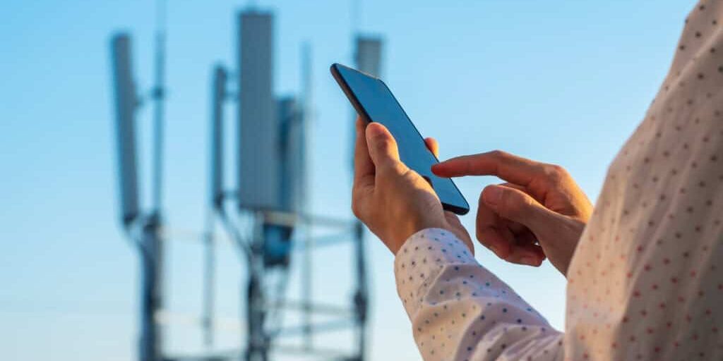 5G communications tower with man using mobile phone